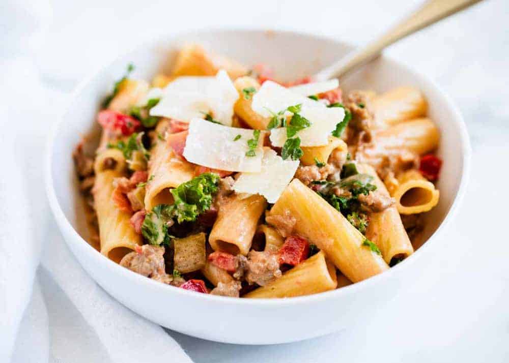 Rigatoni noodles with bolognese sauce in white bowl.