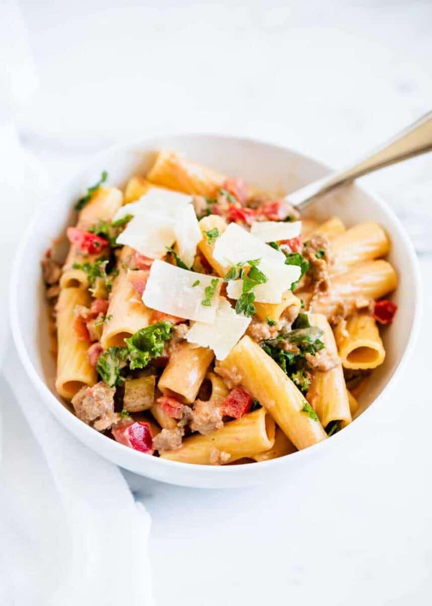 rigatoni noodles with bolognese sauce with parmesan cheese in white bowl