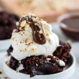 bowl of chocolate cake topped with vanilla ice cream, hot fudge and crushed nuts