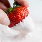 dipping a fresh strawberry into strawberry fruit dip