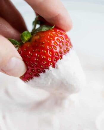 dipping a fresh strawberry into strawberry fruit dip