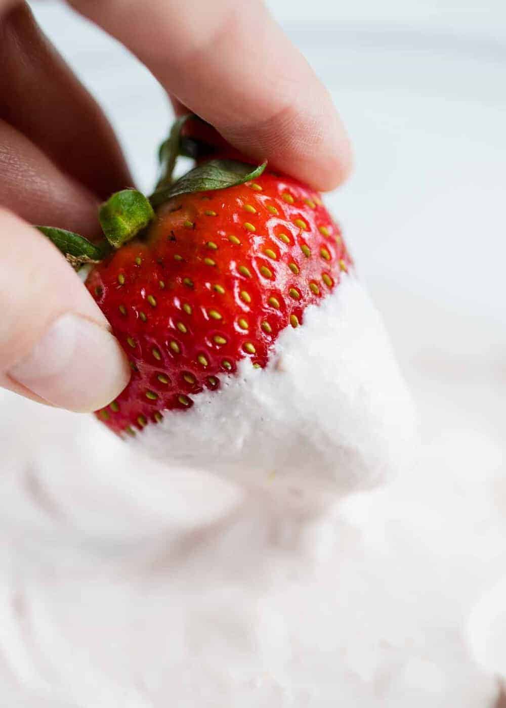 dipping a fresh strawberry into strawberry fruit dip 