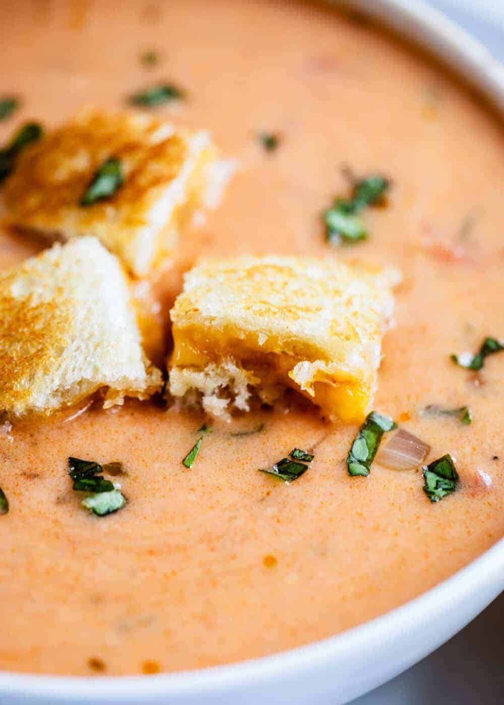 bowl of tomato basil soup with grilled cheese croutons on top