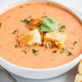 bowl of tomato soup with grilled cheese croutons and fresh basil on top