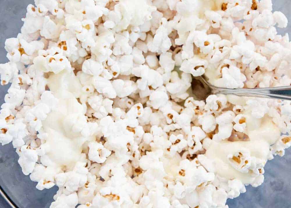 Mixing together popcorn and white chocolate with a fork.