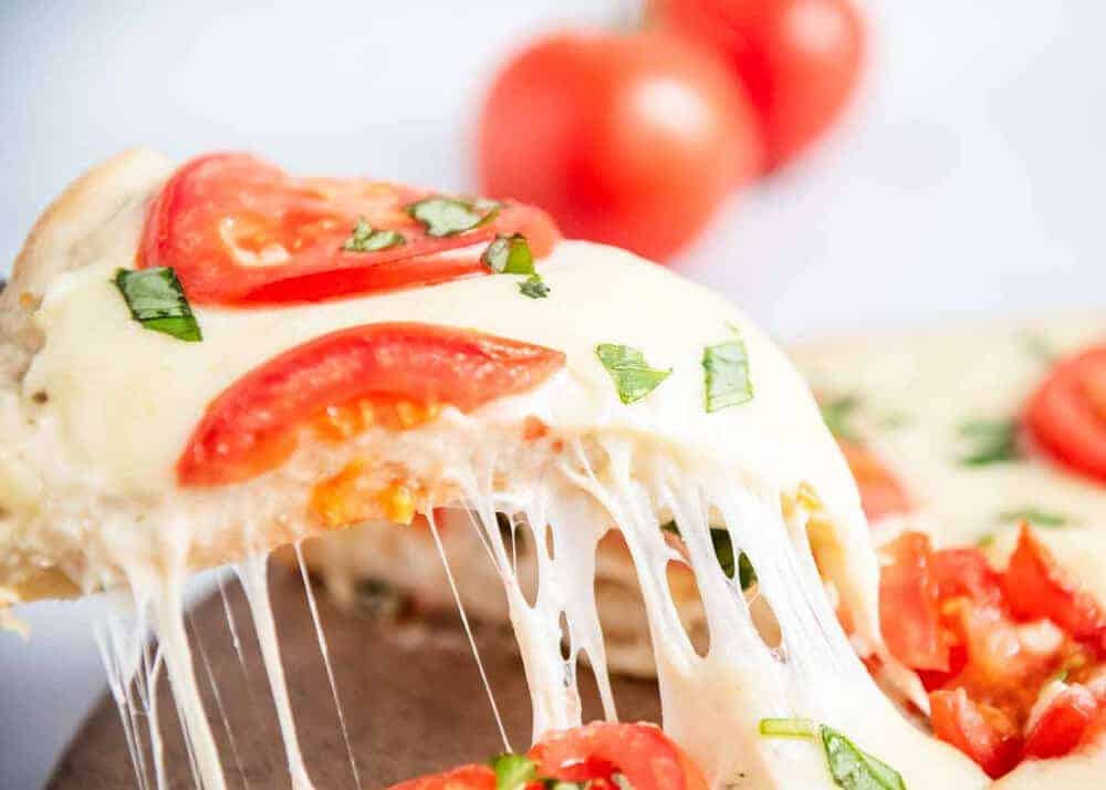 Slice of white pizza with tomatoes and basil.