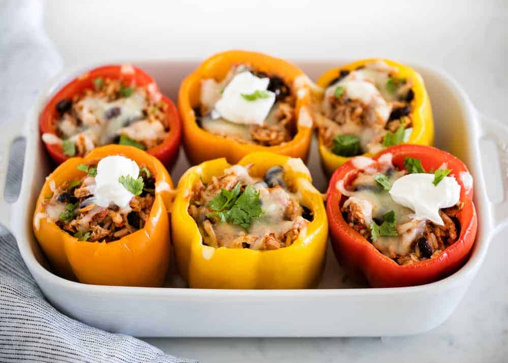 Chicken stuffed bell peppers in a white baking dish.