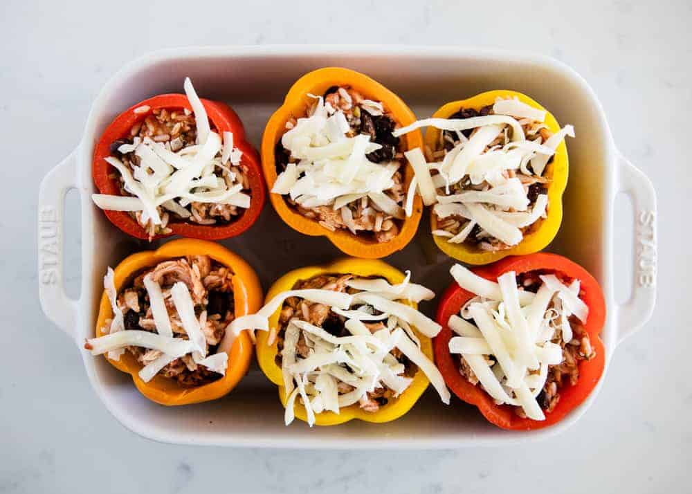 Chicken stuffed peppers in pan with shredded cheese on top.