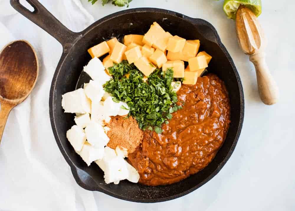 Ingredients for chili queso dip in a cast iron skillet.