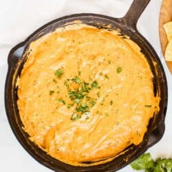 cream cheese and chili queso dip in a cast iron skillet