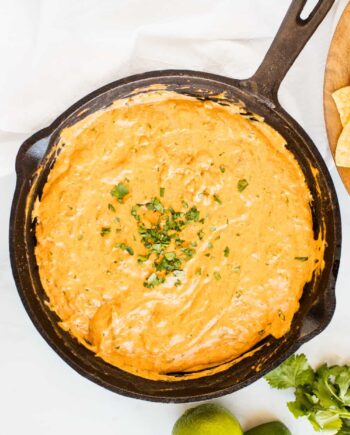 cream cheese and chili queso dip in a cast iron skillet