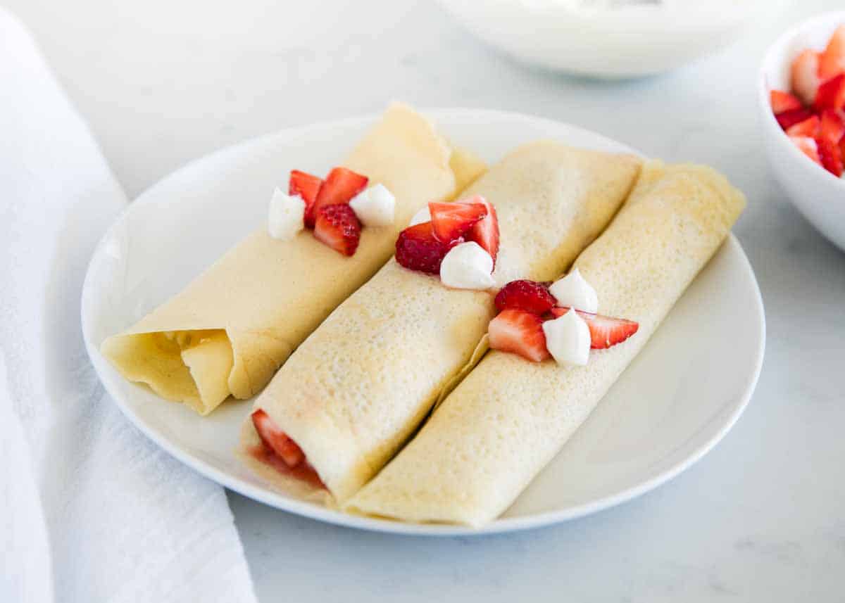 Cream Cheese Crepe Filling - A sweet crepe filling that's creamy, rich and reminiscent of cheesecake. Only 4 ingredients and 5 minutes to make! Crepes with crepe filling on plate.