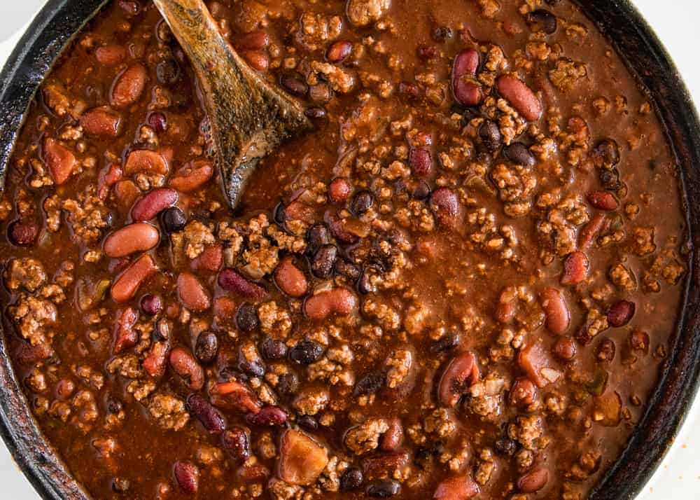 making homemade chili in a cast iron skillet with a wooden spoon 