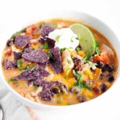 Chicken enchilada soup in white bowl with toppings.