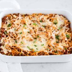 Baked spaghetti with hearty meat sauce and cheeses baked in a casserole dish.