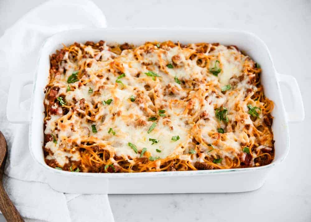 Baked spaghetti in white casserole dish.