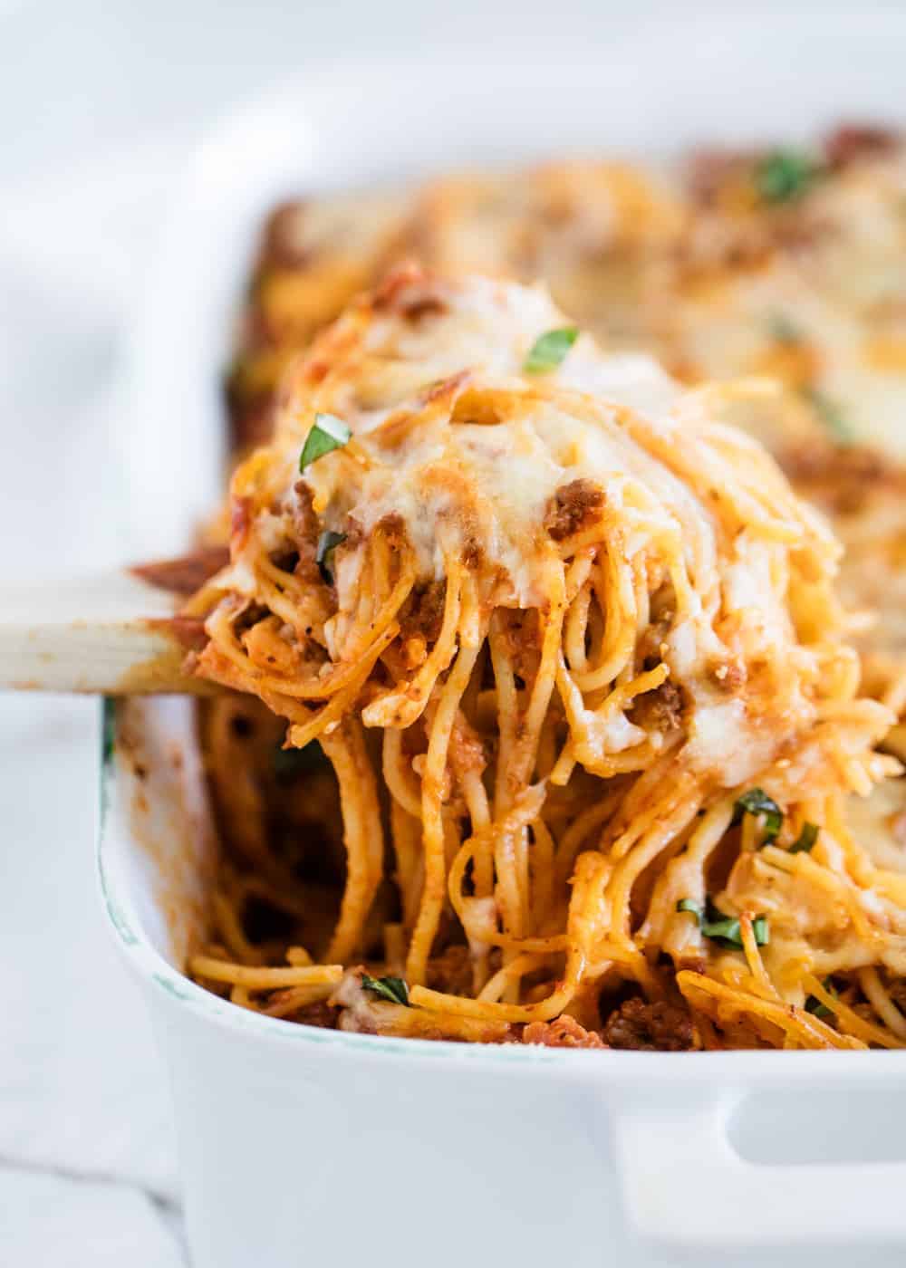 Baked spaghetti being dished out of pan.