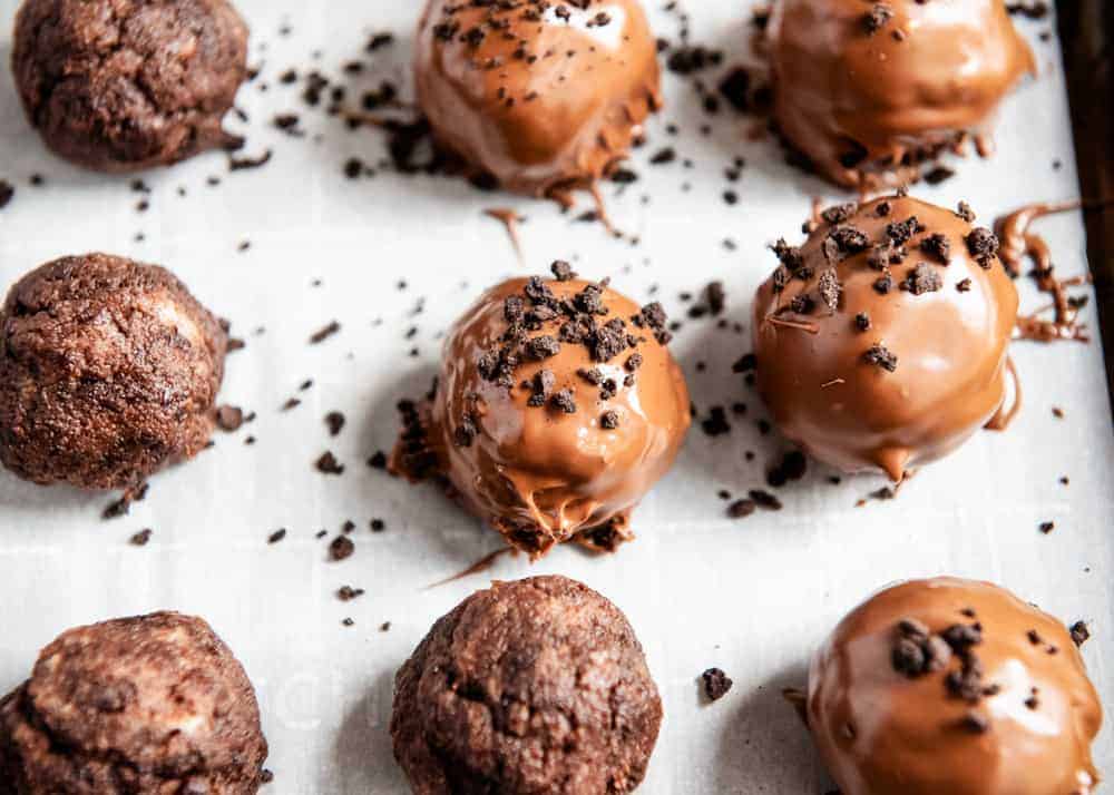 pacing chocolate coated brownie balls on a baking sheet 