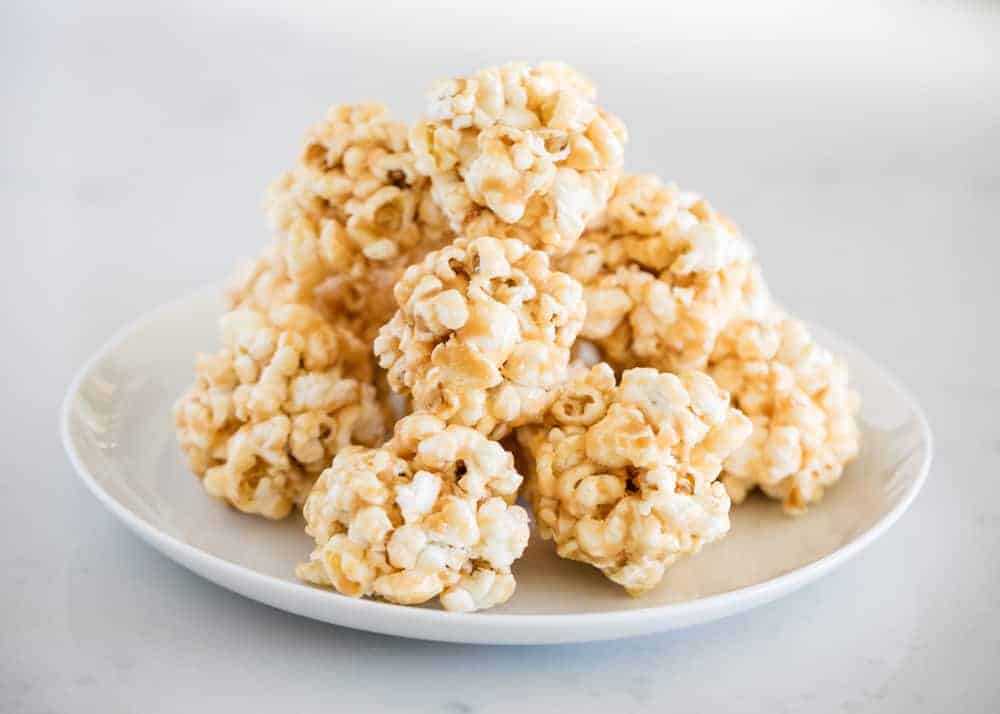 stack of caramel popcorn balls on a white plate 