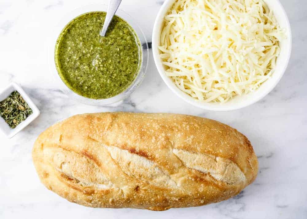 Ingredients for pesto bread on a marble counter top.