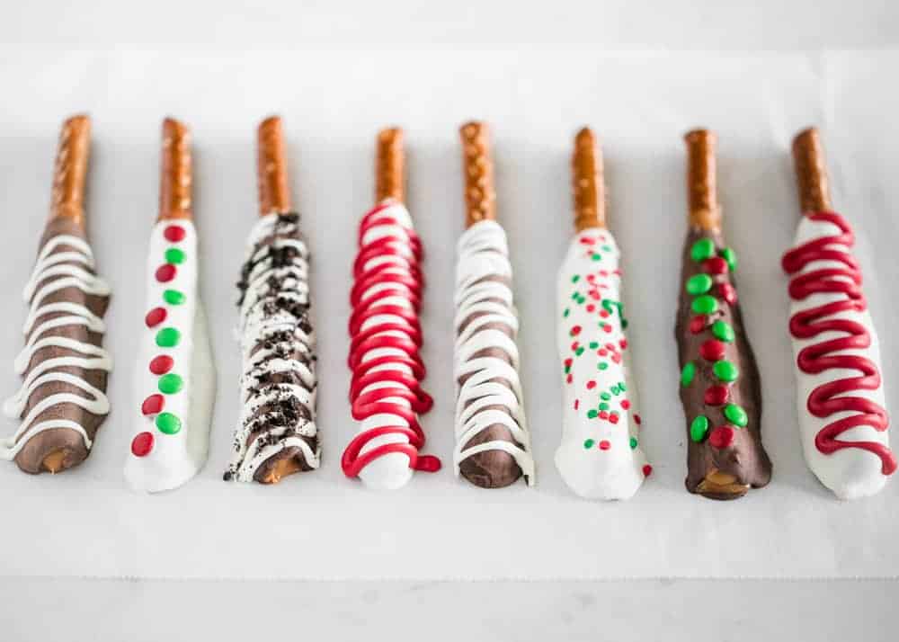 Chocolate covered pretzel rods on parchment paper.