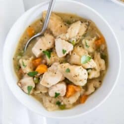 chicken and dumplings in a white bowl with spoon