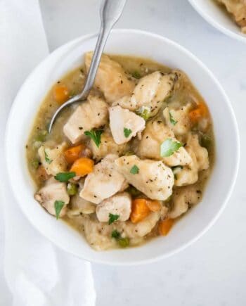 chicken and dumplings in a white bowl with spoon