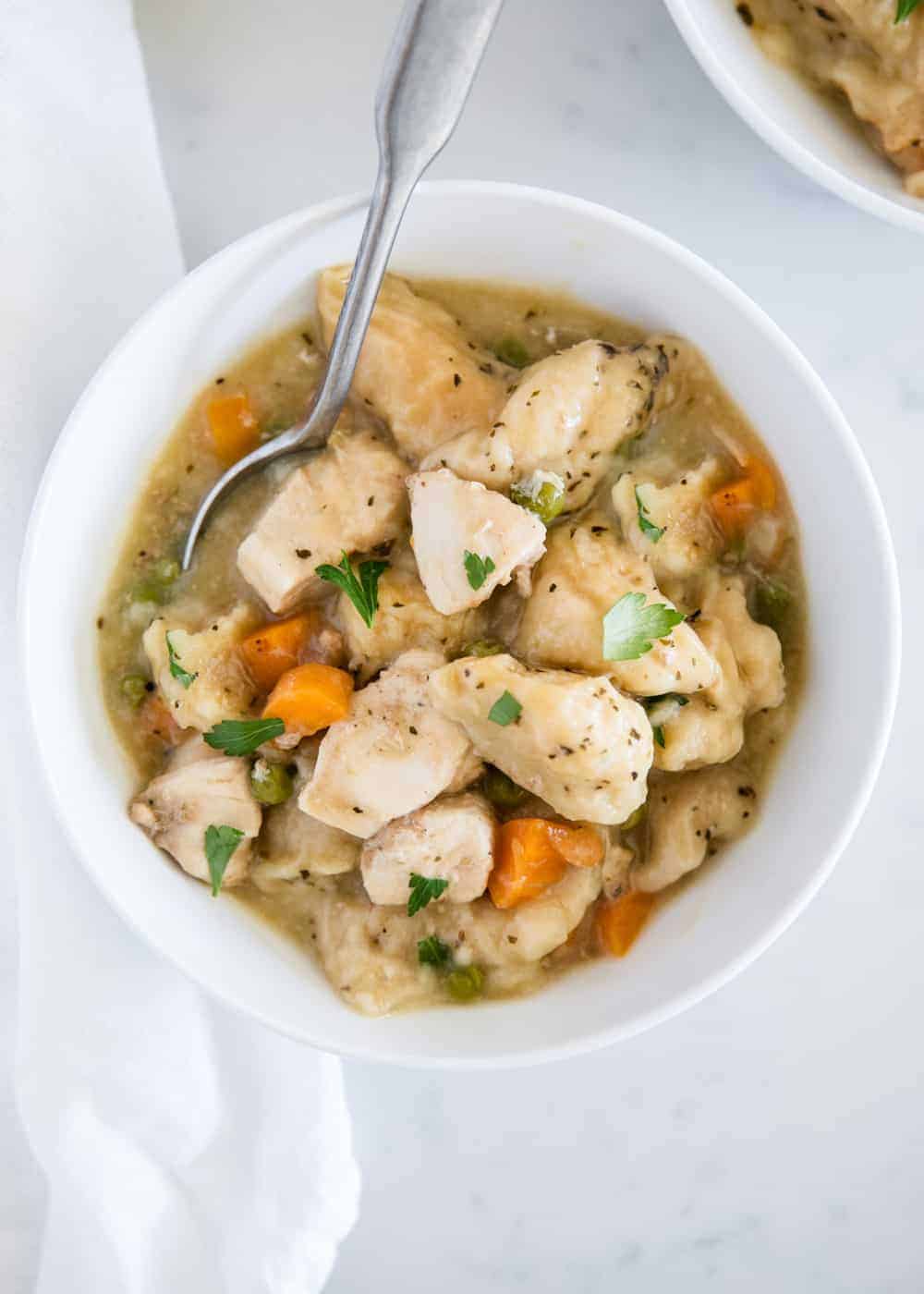 chicken and dumplings in a white bowl with spoon