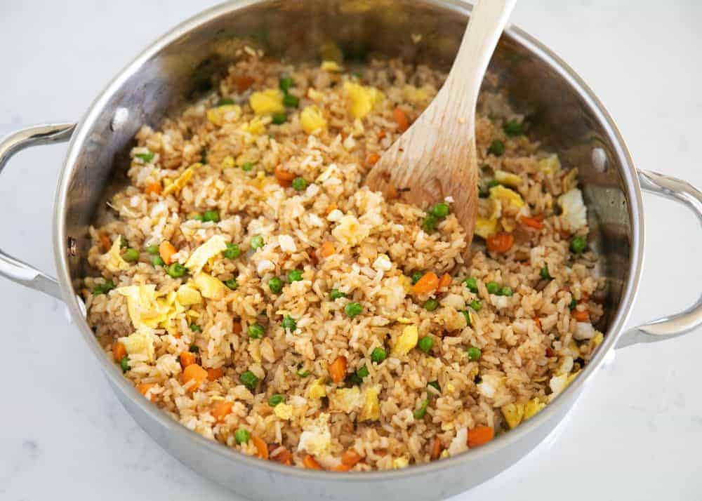A pot of fried rice with a wooden spoon in it.