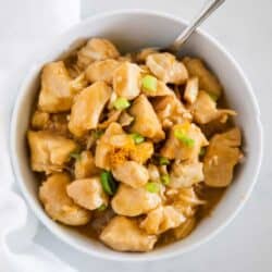 orange chicken with green onions in white bowl