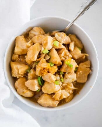 orange chicken with green onions in white bowl