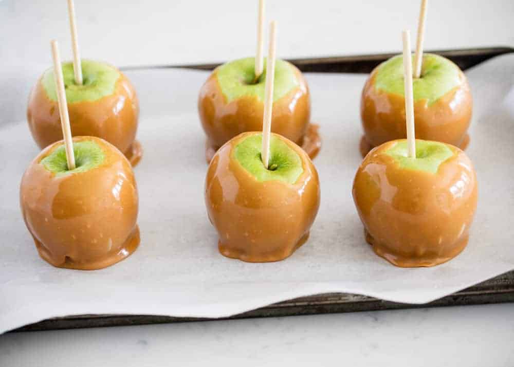 Homemade caramel apples on a baking sheet.