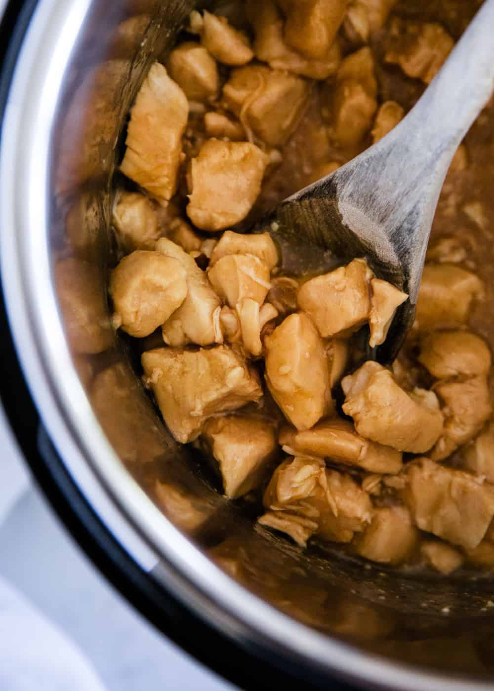 instant pot orange chicken with a wooden spoon 