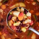 scooping minestrone soup with a silver ladle