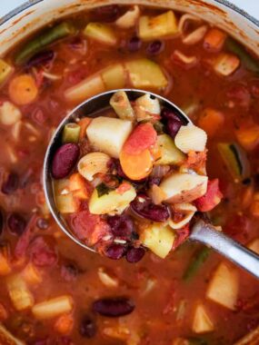 scooping minestrone soup with a silver ladle