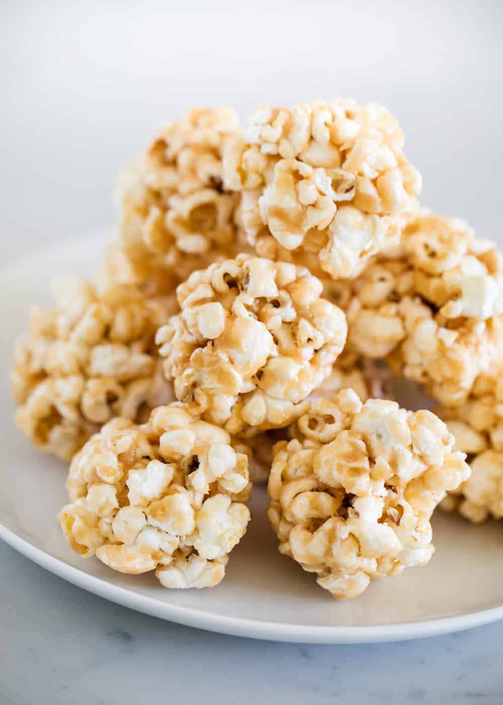 Popcorn balls stacked on white plate.