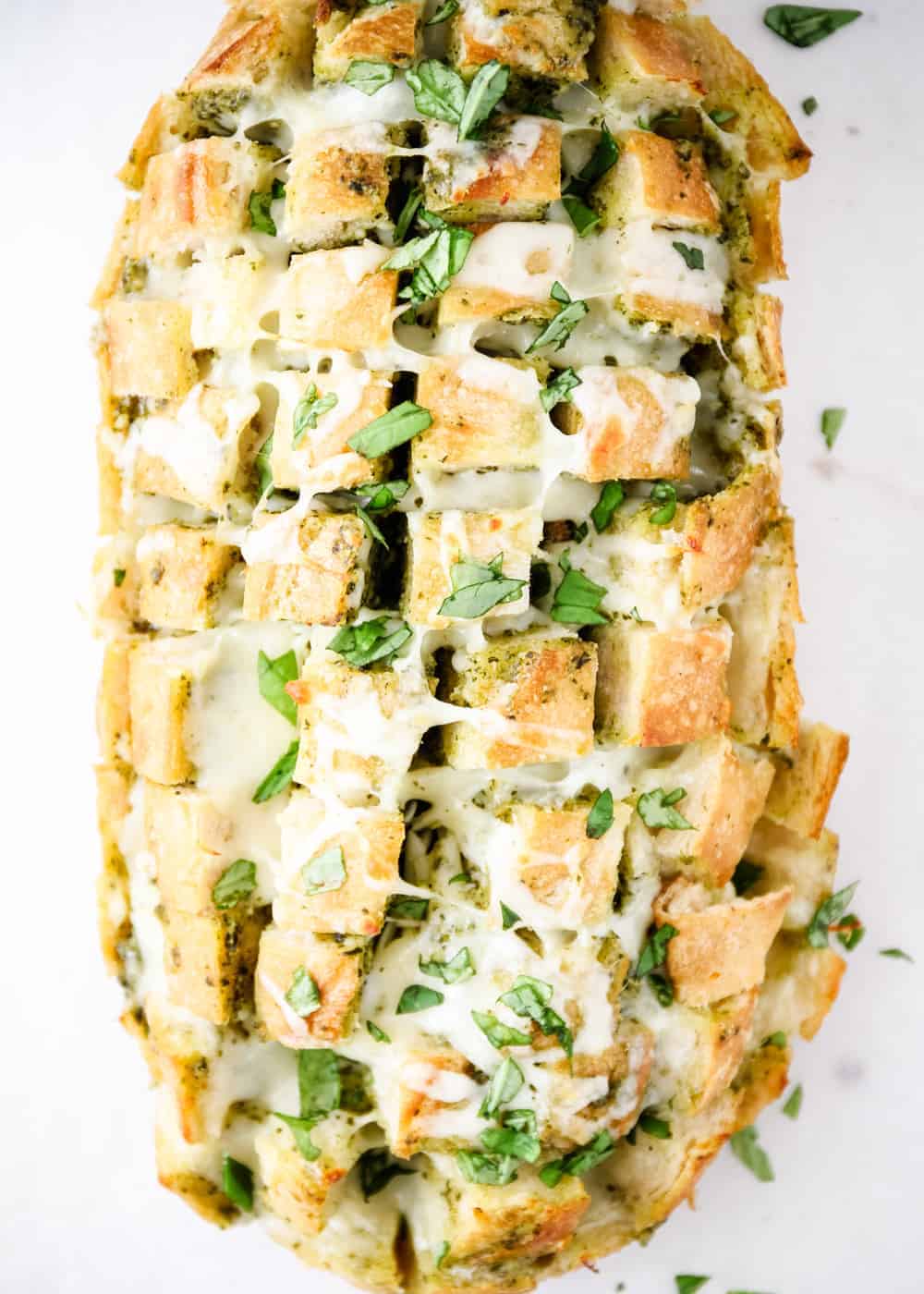 Loaf of cheesy pull-apart bread with fresh basil on top.