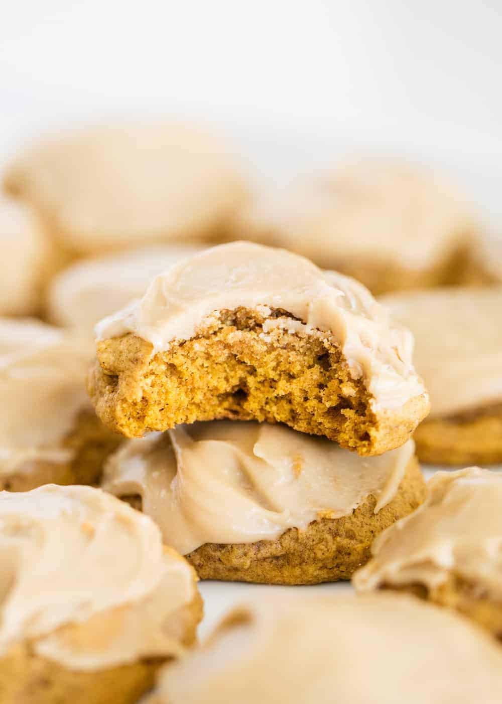 Iced pumpkin cookies with a bite taken.