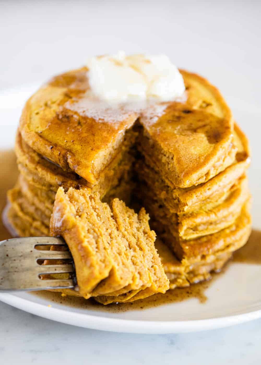 Stack of pumpkin pancakes with butter and syrup.