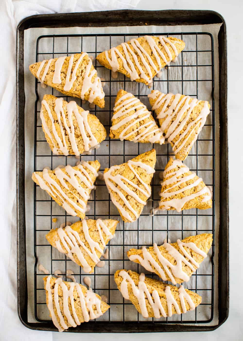pumpkin scones on cooling rack with glaze drizzled on top 