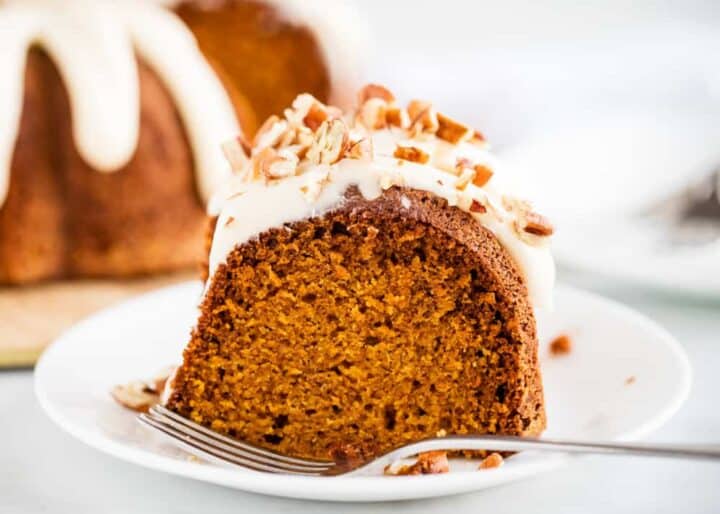 piece of pumpkin bundt cake with cream cheese frosting on a white plate 