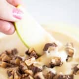 Dippin an apple slice into toffee apple dip.