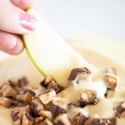 Dippin an apple slice into toffee apple dip.