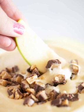 Dippin an apple slice into toffee apple dip.