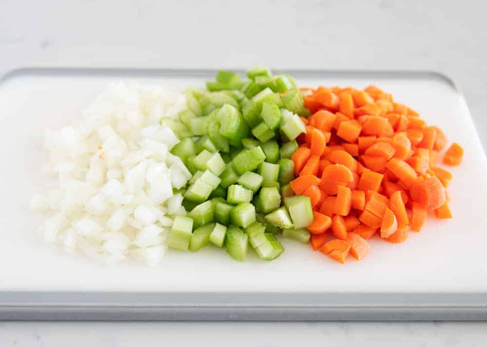 Diced onions, celery and carrots on a cutting board. 