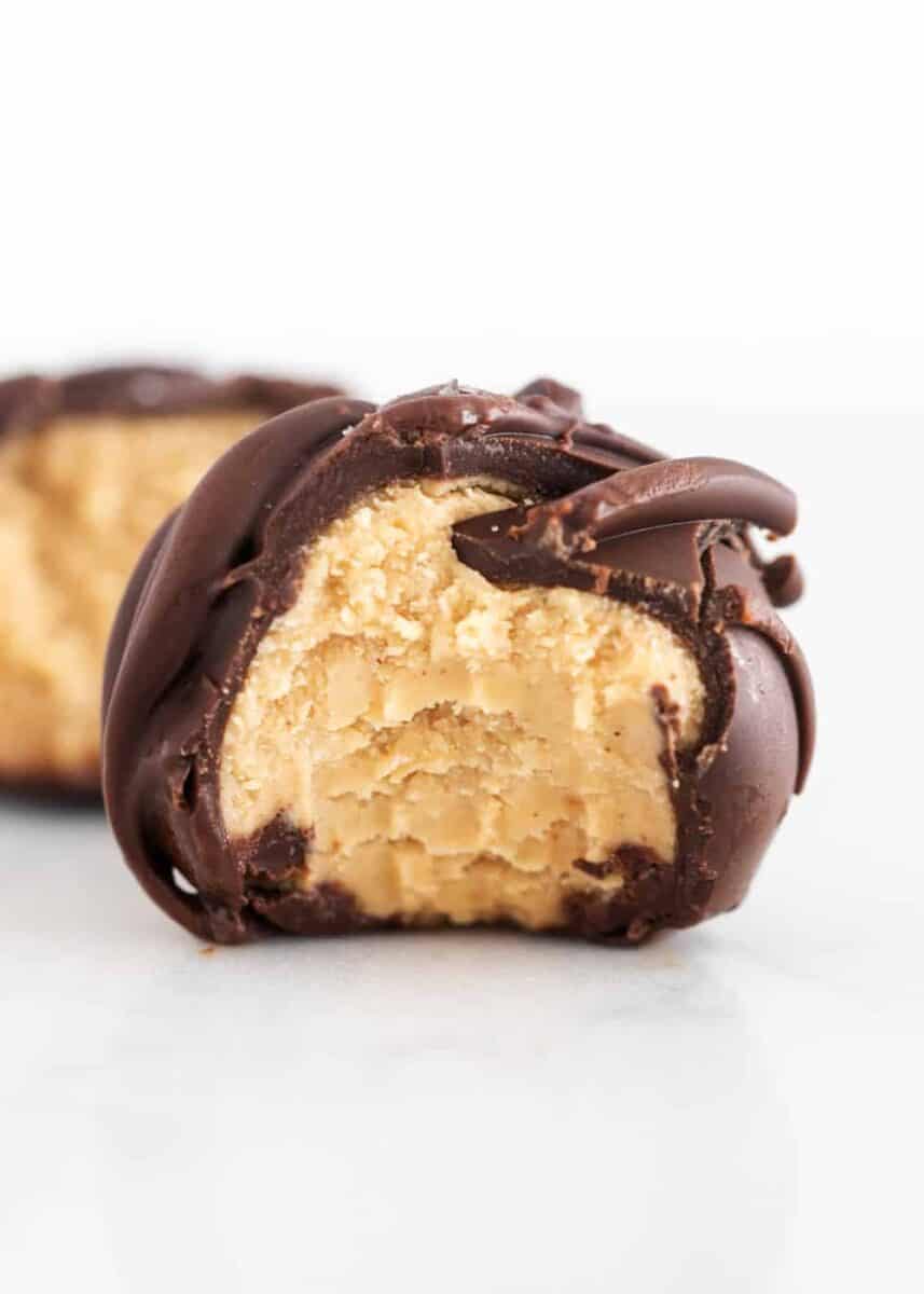 Creamy peanut butter balls covered in a sweet chocolate coating with a dash of sea salt. This delicious treat is always the first gone at a party! chocolate peanut butter ball with a bite taken