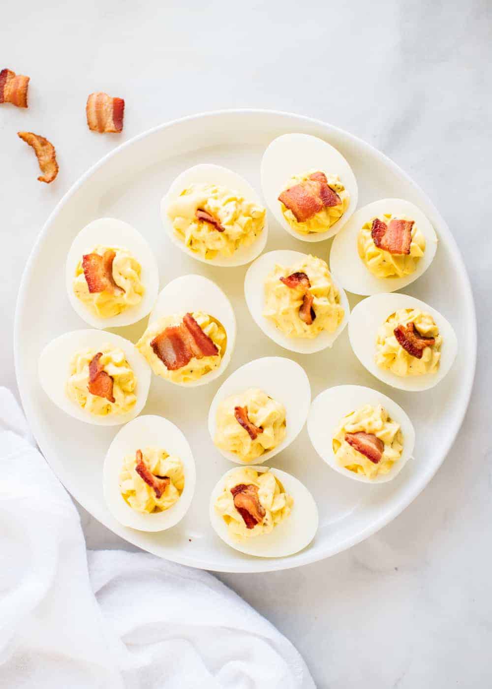 ranch deviled eggs with bacon on a white plate 