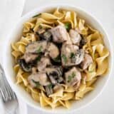 beef stroganoff served over egg noodles in a white bowl