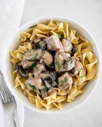 beef stroganoff served over egg noodles in a white bowl