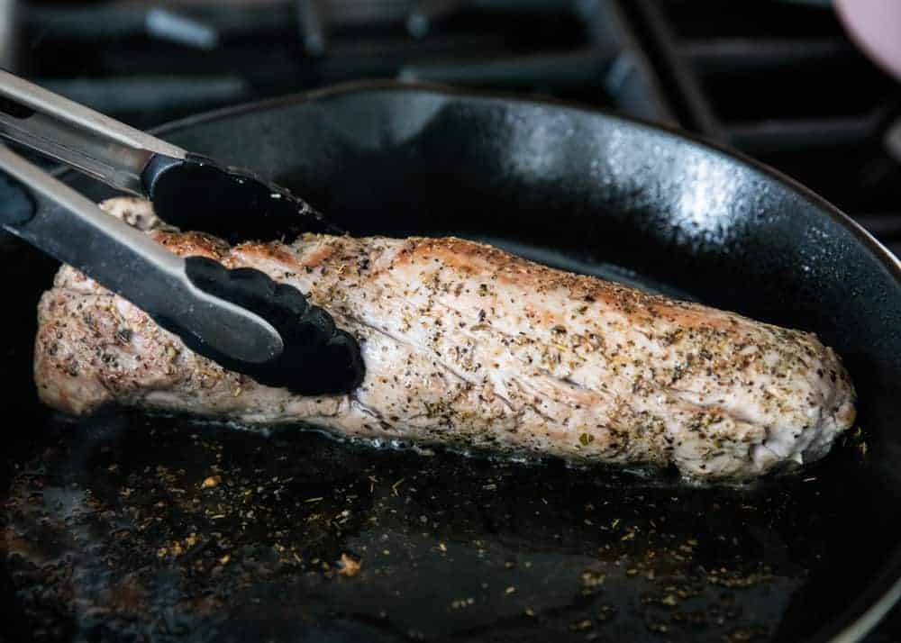 Searing the pork tenderloin in a cast iron skillet.